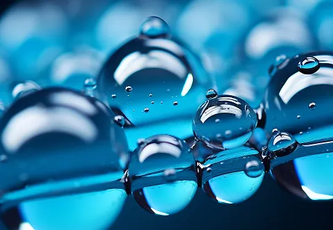Close-up image of several clear water droplets resting on a smooth blue surface, showing reflections and refractions of light.